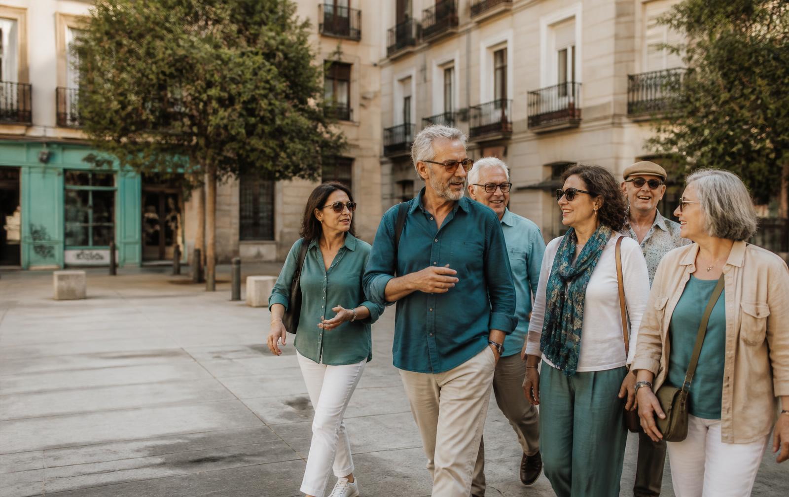 Grupo diverso de personas mayores de 55 años paseando y conversando en una plaza de Madrid